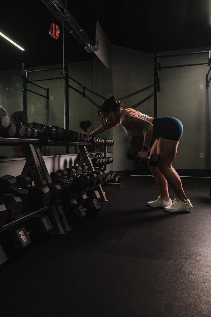 A woman performs a bent-over row with dumbbells in a gym, exemplifying strength and fitness.